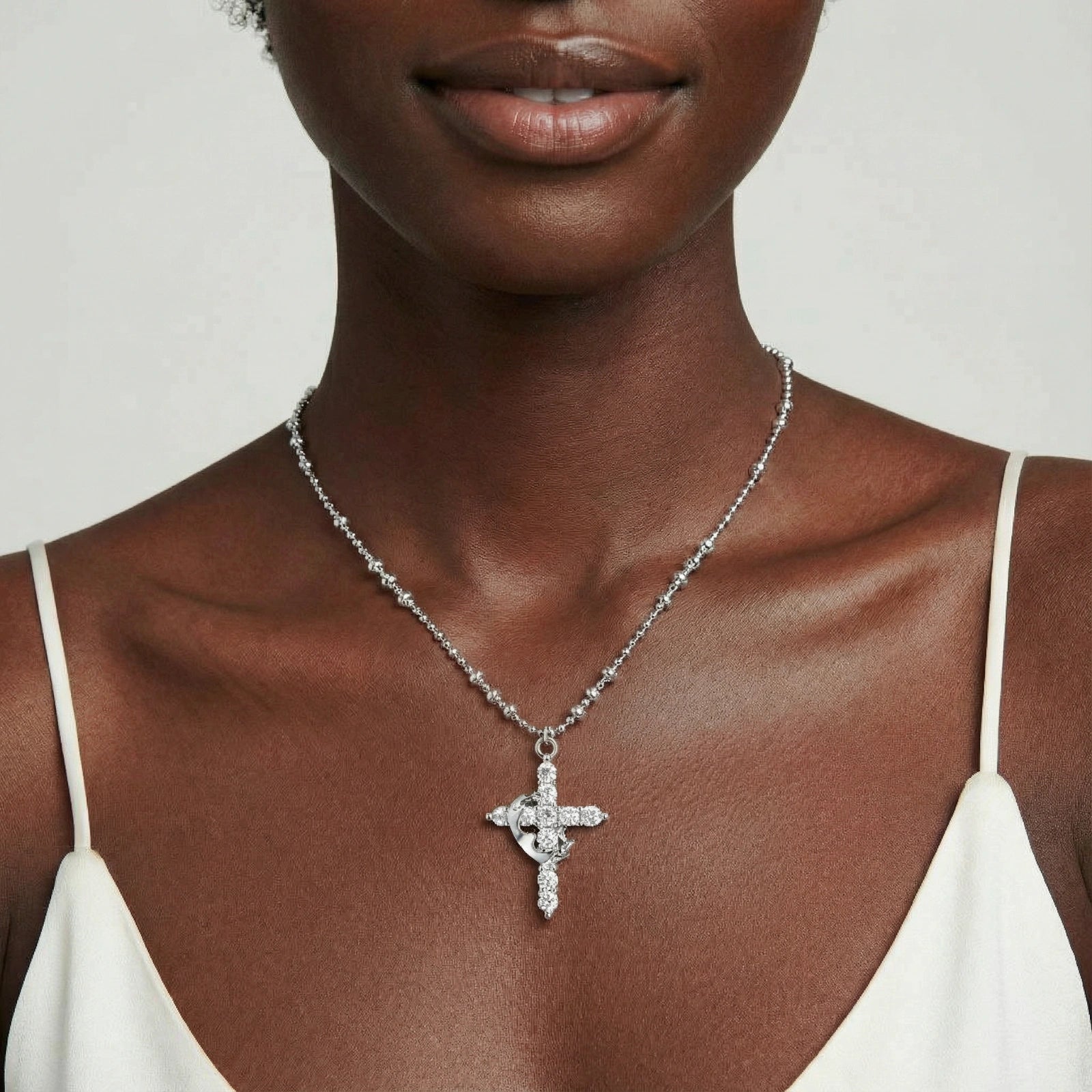 White gold-plated cross pendant adorned with sparkling zirconia stones and crescent moon accent on ball chain