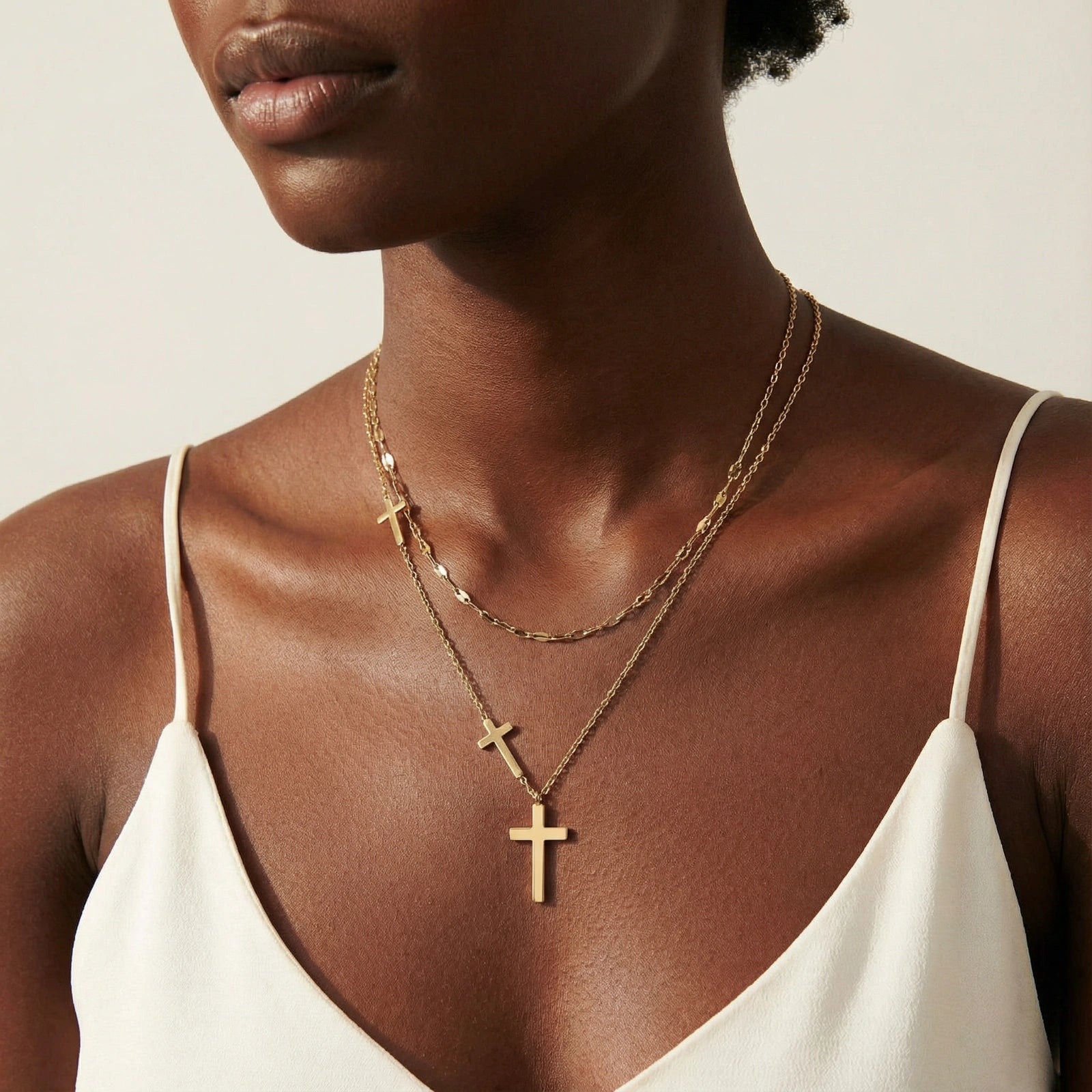 Three-layered gold necklace set with graduated cross pendants in mixed chain styles on white background.